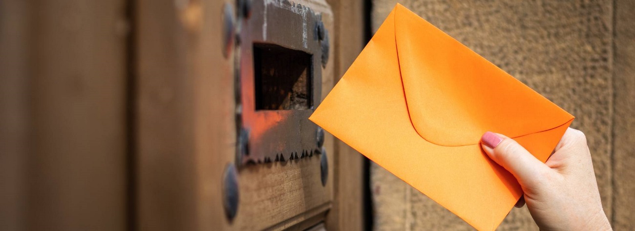 hand inserting an envelope into a mail slot